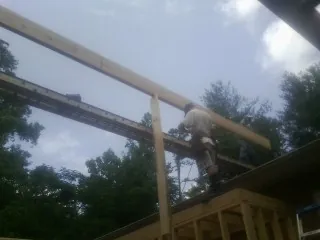 Carpenter setting a ridge beam over a new addition frame — Ice Dam Removal by Roofing Brothers in Fort Pierce