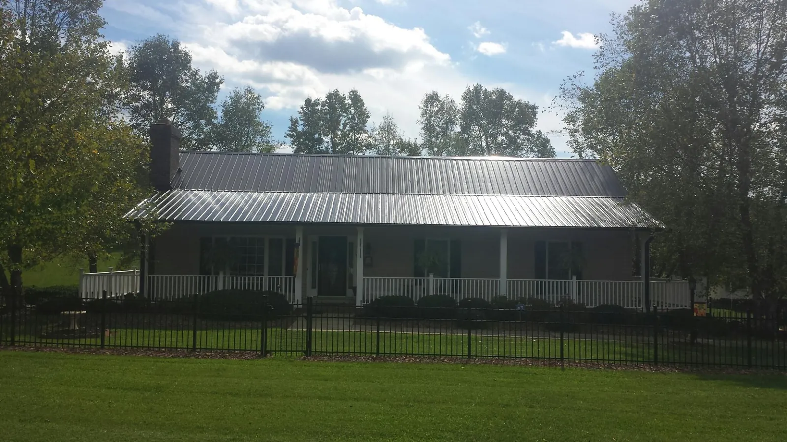 Gray metal roof on a brick ranch with a full width front porch — Gutter Guard Installation work by our crew in Fort Pierce