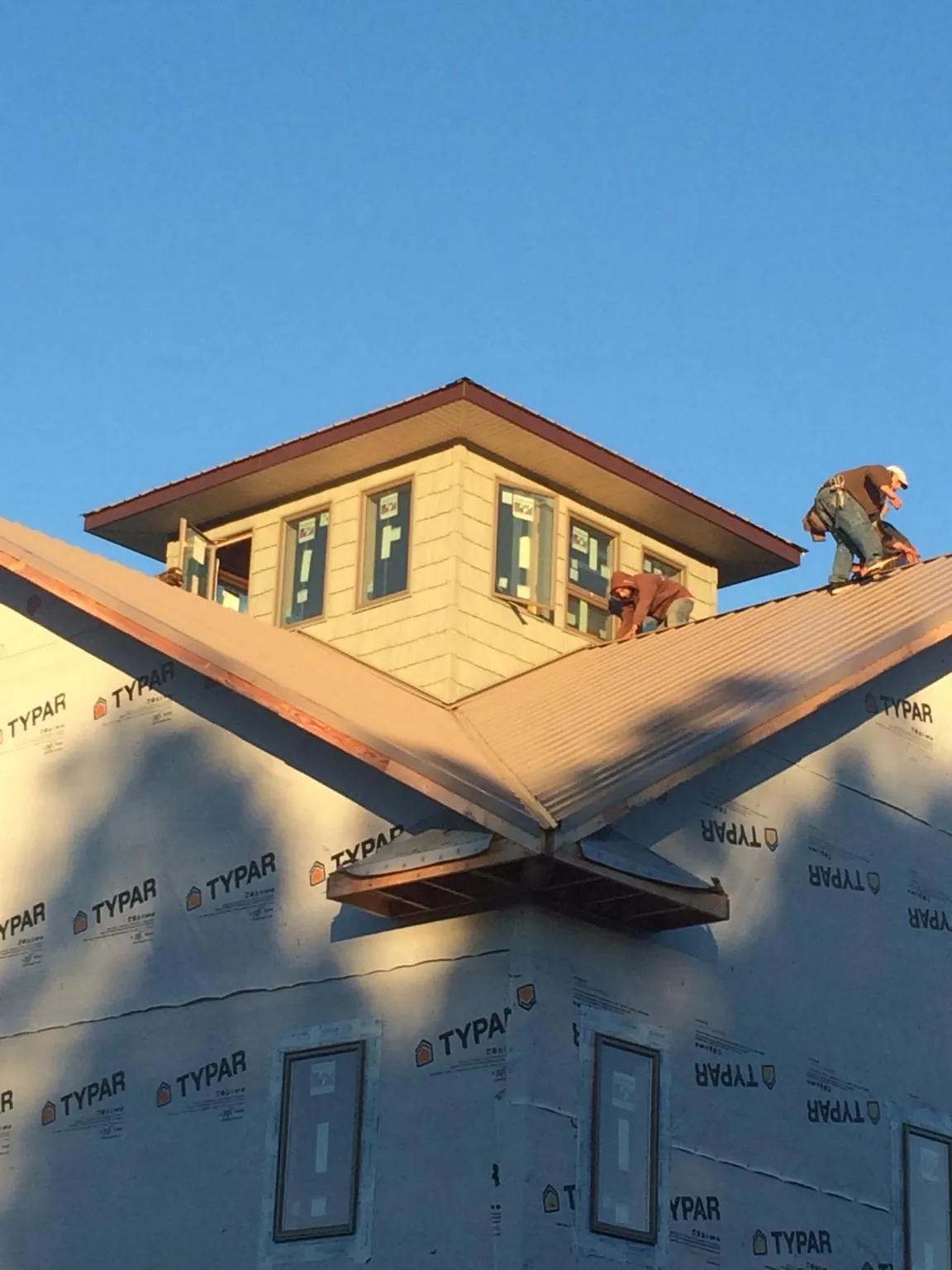 Roofers working around a rooftop cupola on a new metal roof at sunset — Roof Waterproofing in Fort Pierce by Roofing Brothers